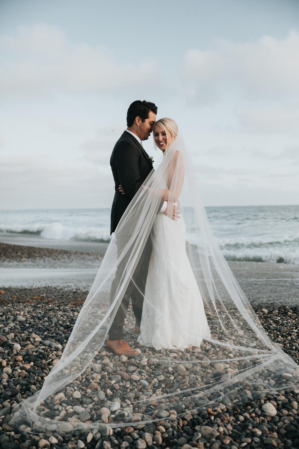 Bride and groom sharing a tender moment beside the ocean